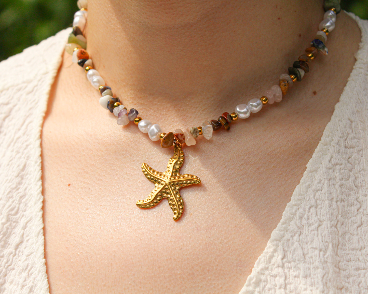 Necklace with a gold starfish pendant worn by a person