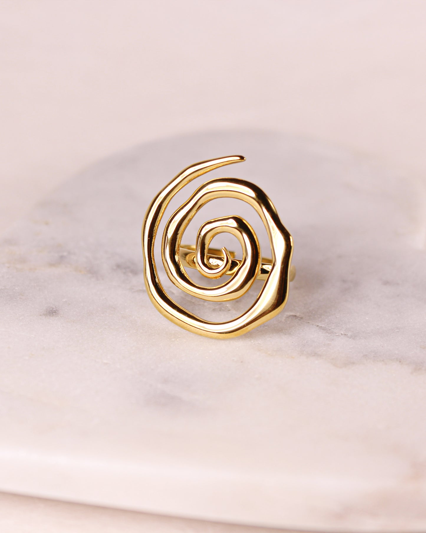 Gold spiral ring on a marble surface