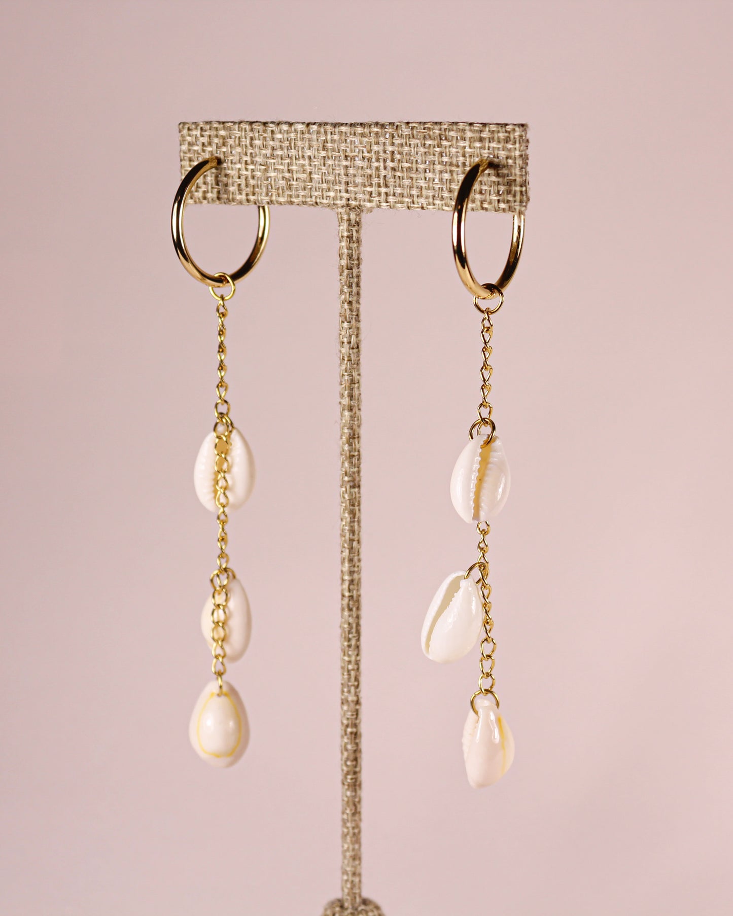 Gold earrings with pearl drops on a pink background
