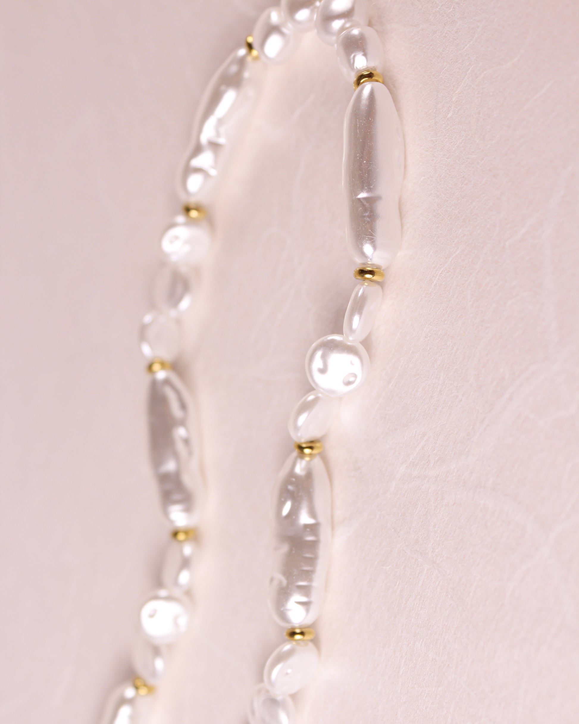 Pearl necklace with gold accents on a light pink background