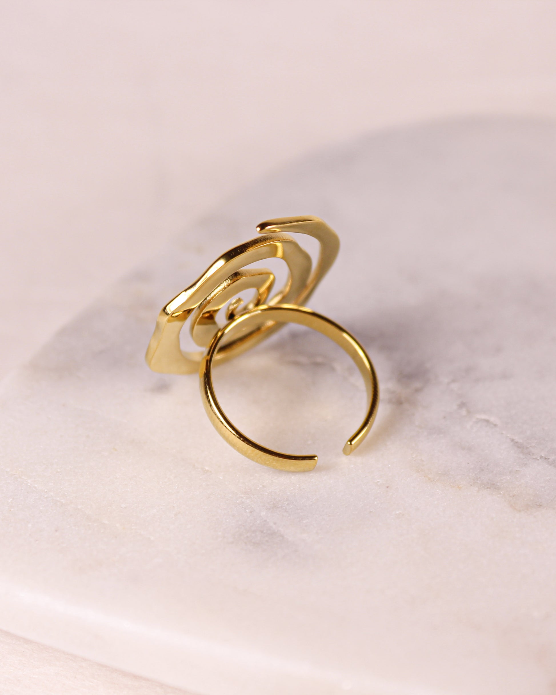 Gold ring with a unique design on a light marble background