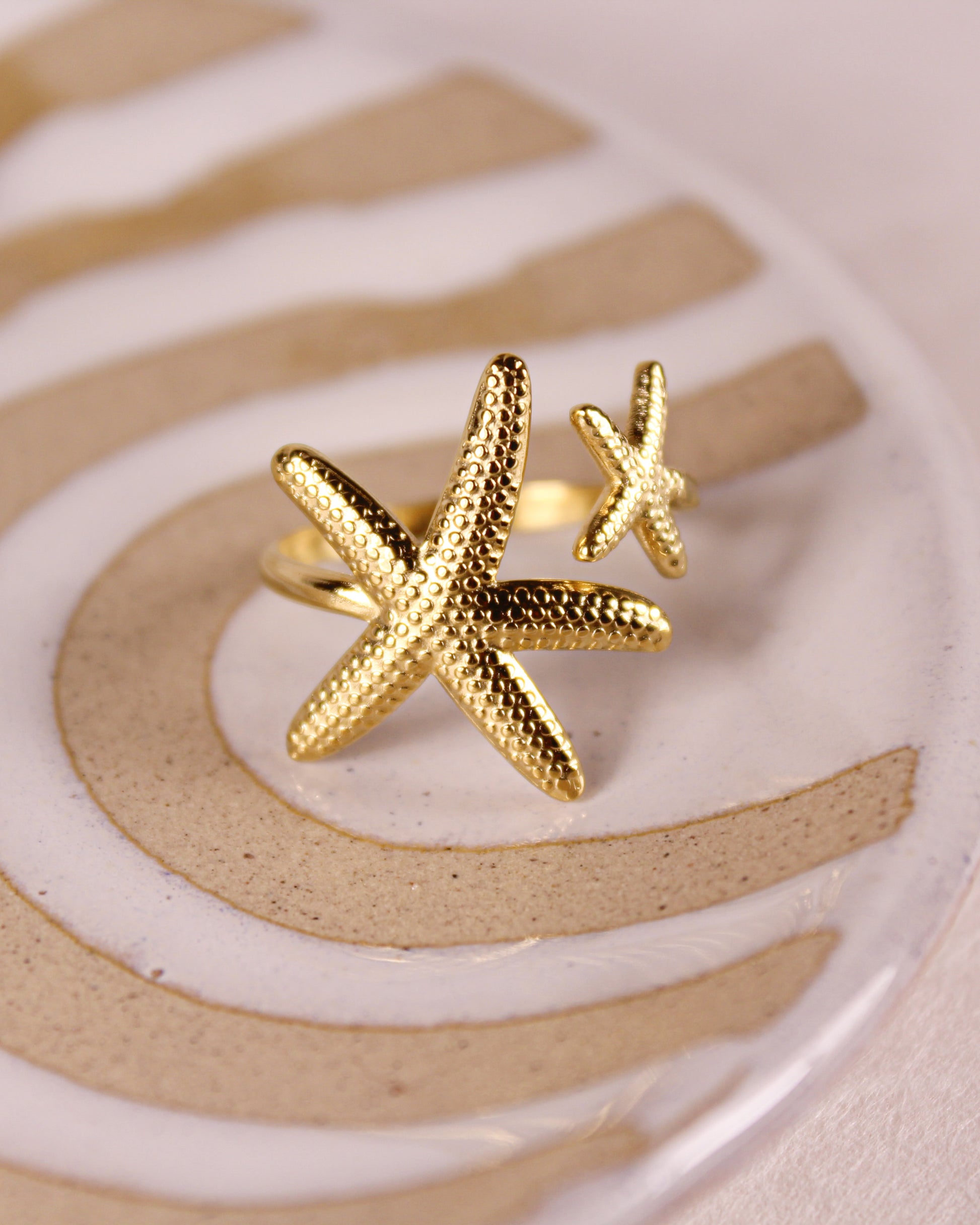 Gold starfish-shaped ring on a textured surface